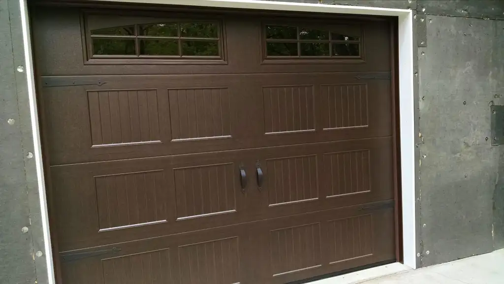 Dark brown carriage-style garage door with a row of window lites, newly installed