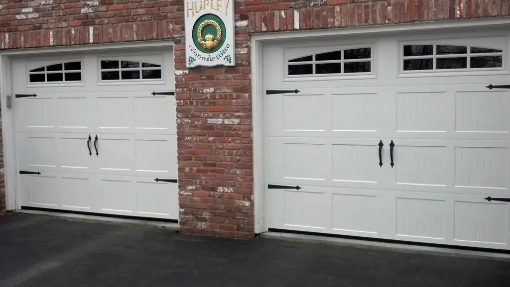 Two cream carriage-style garage doors with window lites set into a brick garage front