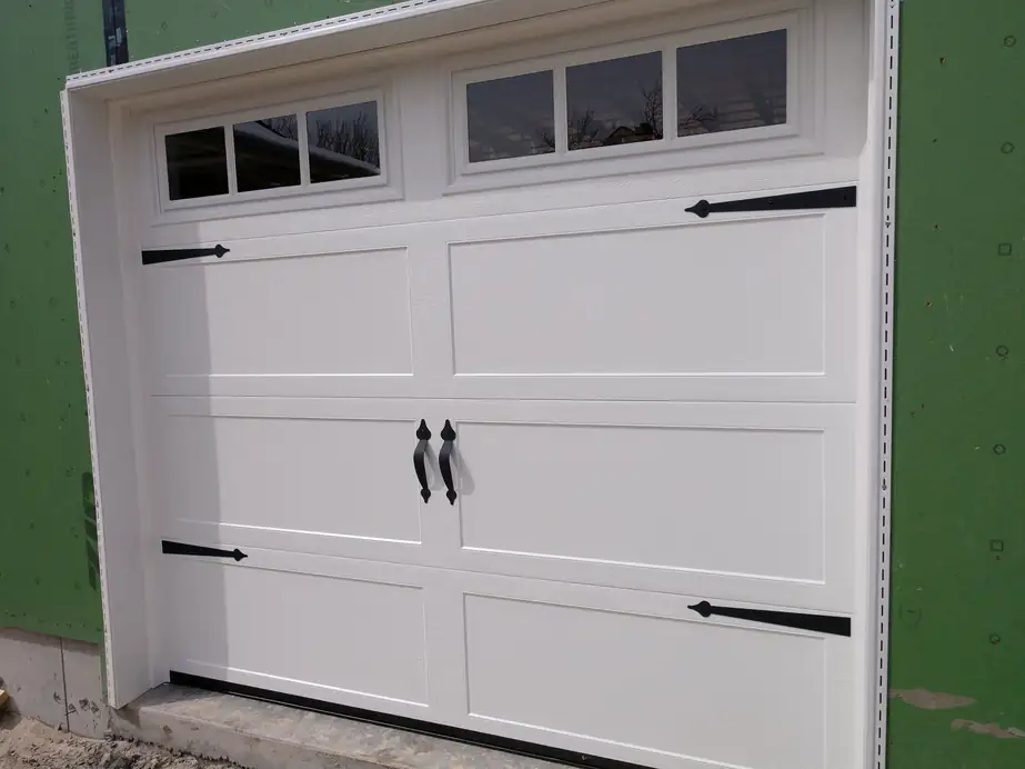 Black strap hinges and handles on a white carriage-style garage door